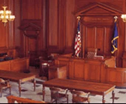 A wood-paneled courtroom with American and state flags
